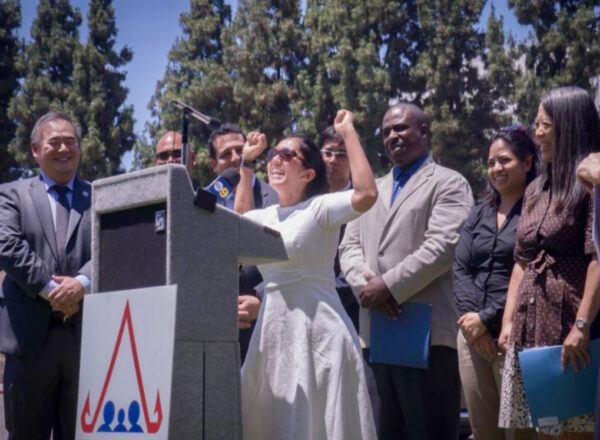 Rotchana "Mama" Sussman giving a speech at a podium with people beside her.