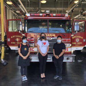 three people standing in front of a fire dept truck