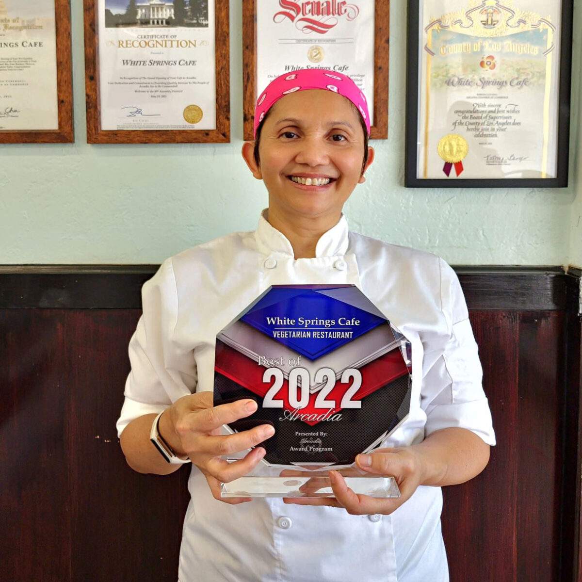 Rotchana, owner of White Springs Cafe holding an award for being Best Vegetarian, Vegan, Thai Food, and best Appetizer Restaurant