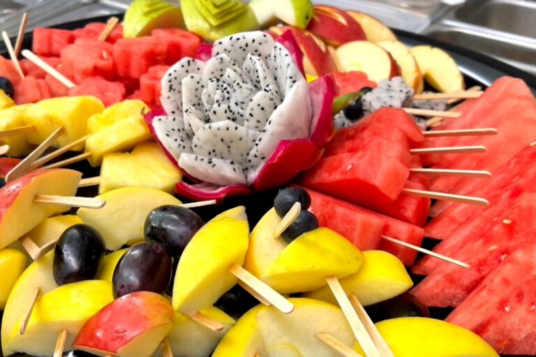 various cut fruits with skewers on a round black platter
