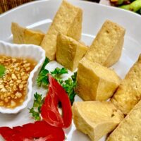 Fried tofu with sweet & sour sauce on a white plate