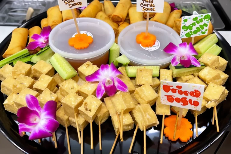 skewered tofu cubes and spring rolls on a round platter