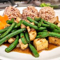 green beans with mushrooms, tofu and rice on a plate