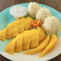 sliced mangos and sticky rice balls on a plate