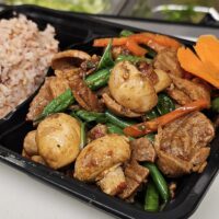 mushroom with tofu chunks in a black take-out container with rice