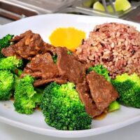 vegan beef on top of steamed broccoli with rice on the side of the plate