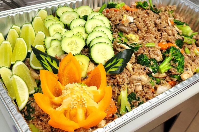 vegetable fried rice in a large aluminum tray with vegetable decorations